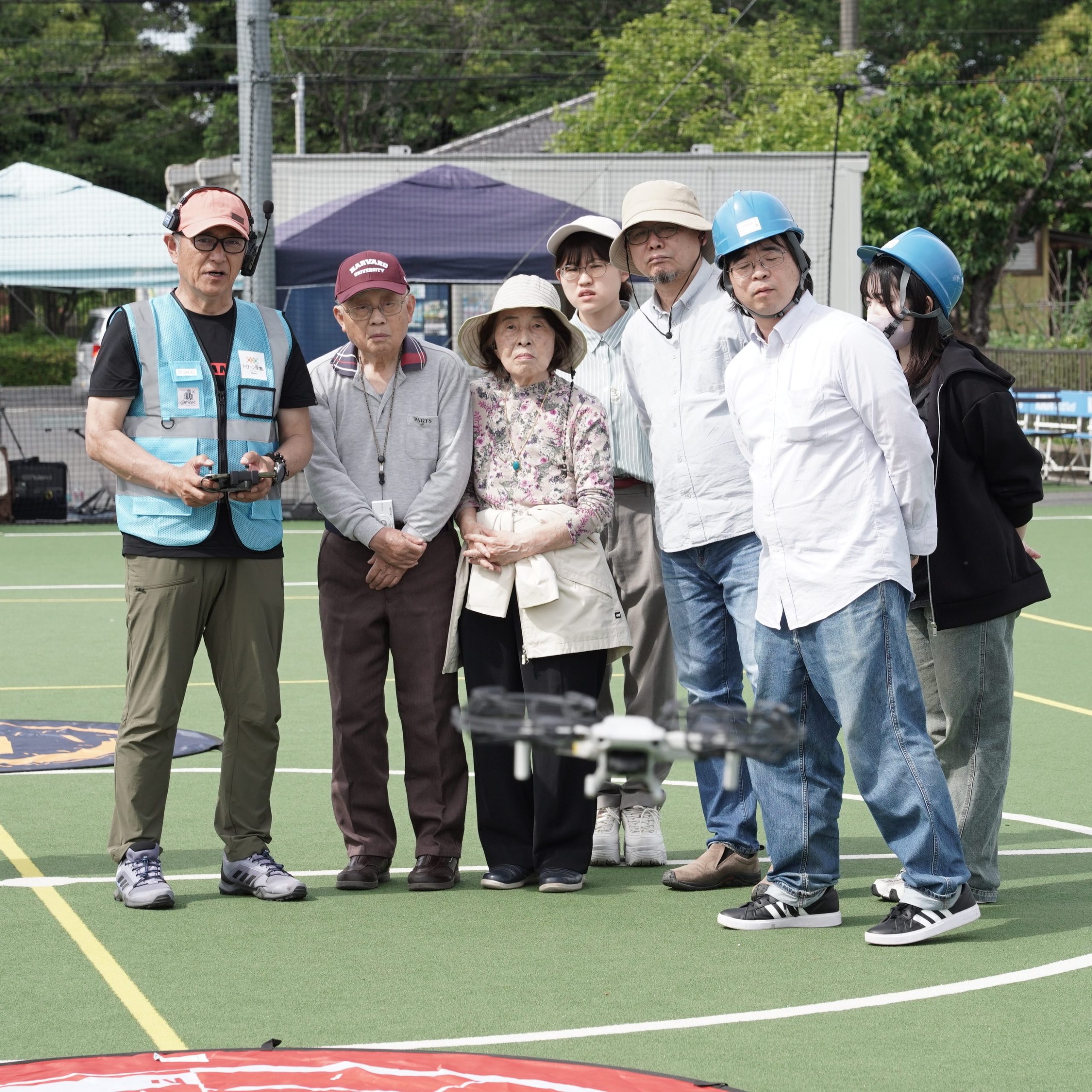 初めてのドローン操縦体験前に、操作手順を説明、ドローンの挙動をくいるように見つめる参加者